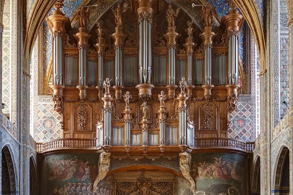Grand buffet d'orgue sculpté et doré au fond de la nef peinte de la cathédrale d'Albi, au-dessus de rangées de bancs