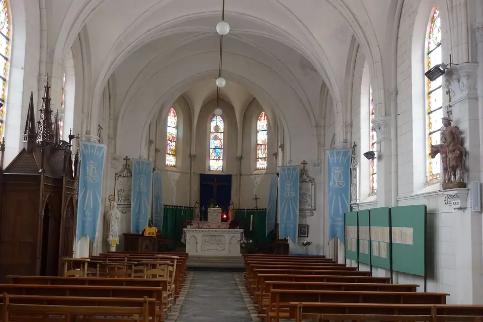 Intérieur clair d'une église de village avec bancs de bois, nef voûtée blanche, vitraux colorés et autel au fond