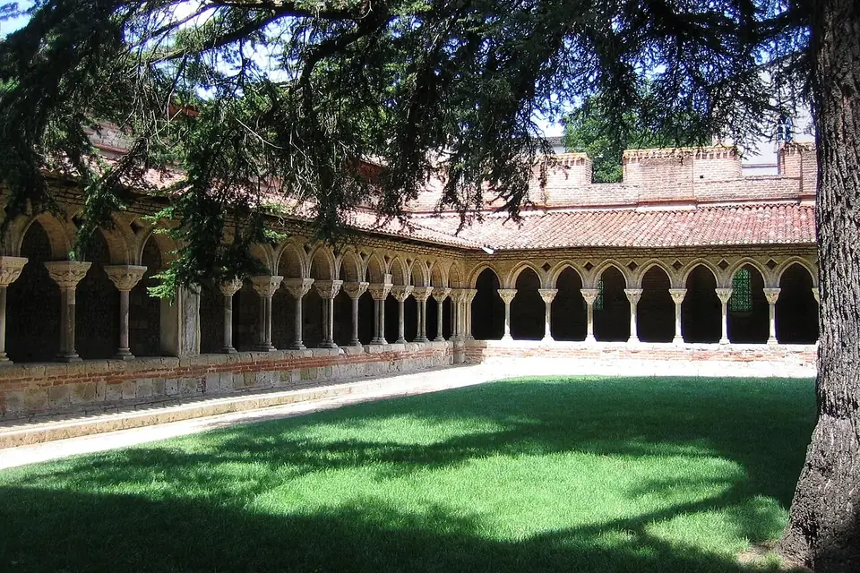 Galerie du cloître de Moissac, avec ses arcades sur colonnettes, vue depuis le jardin ombragé par un grand cèdre