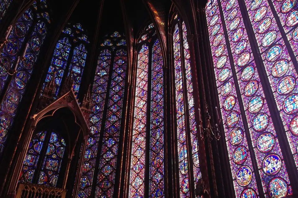 Hautes verrières bleues et rouges de la chapelle haute de la Sainte-Chapelle à Paris, séparées par de fins piliers dorés